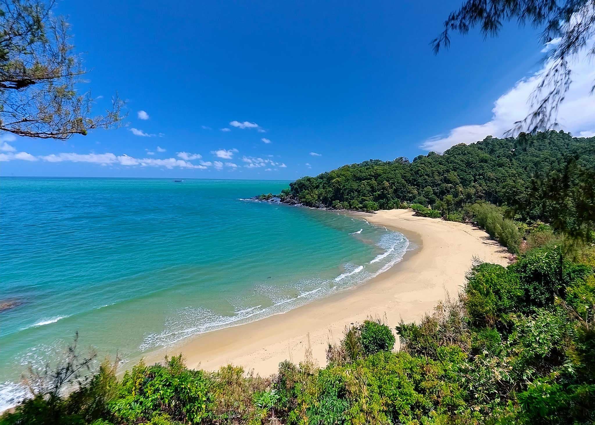 A tranquil beach on Koh Lanta, lined with palm trees and calm turquoise waters