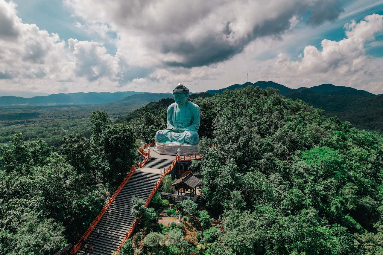 Wat Prathat Doi Prachan Temple Buddha statue in Lampang, Thailand, surrounded by lush greenery.